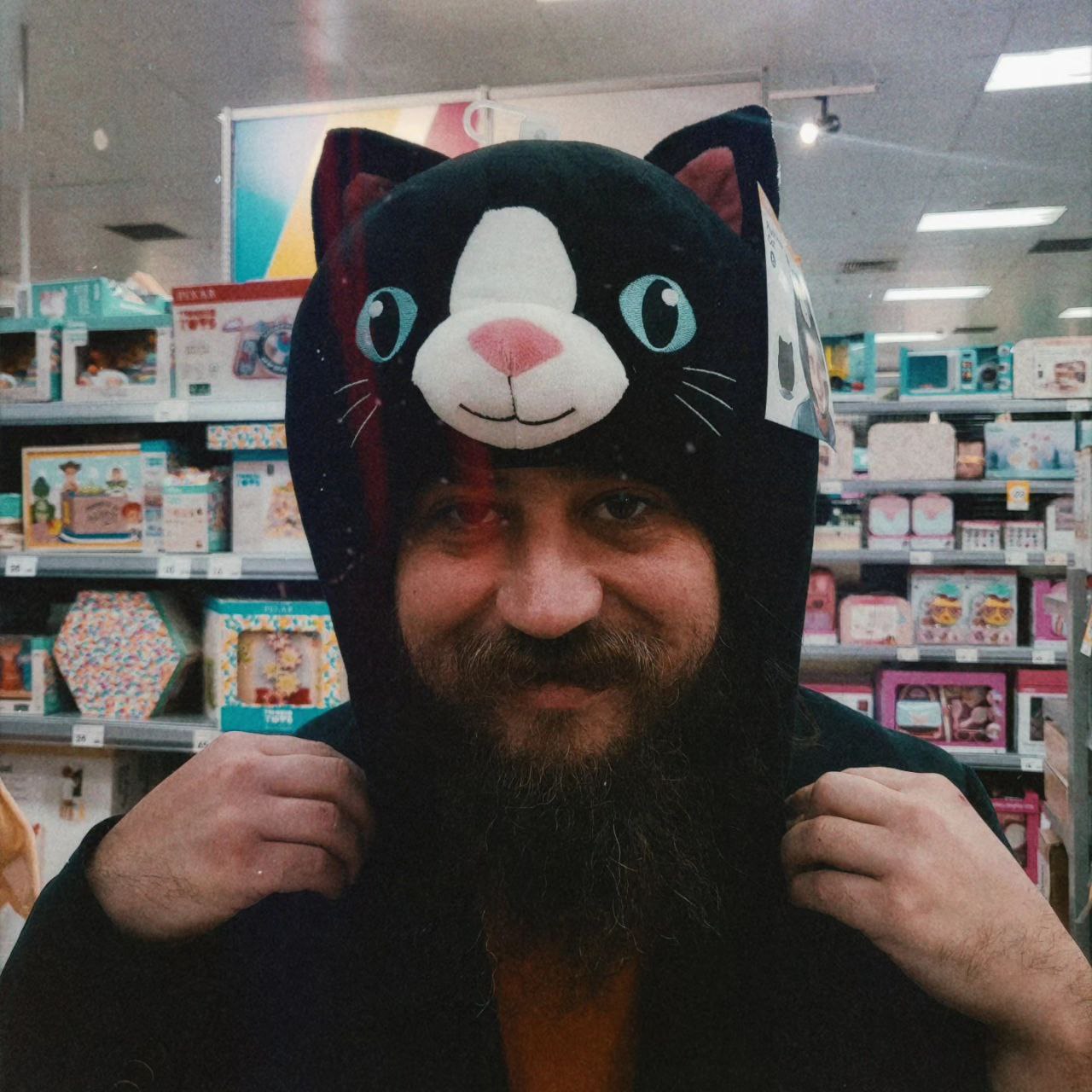 vidak wearing a plushy cat hat. vidak has a big beard and moustache. 