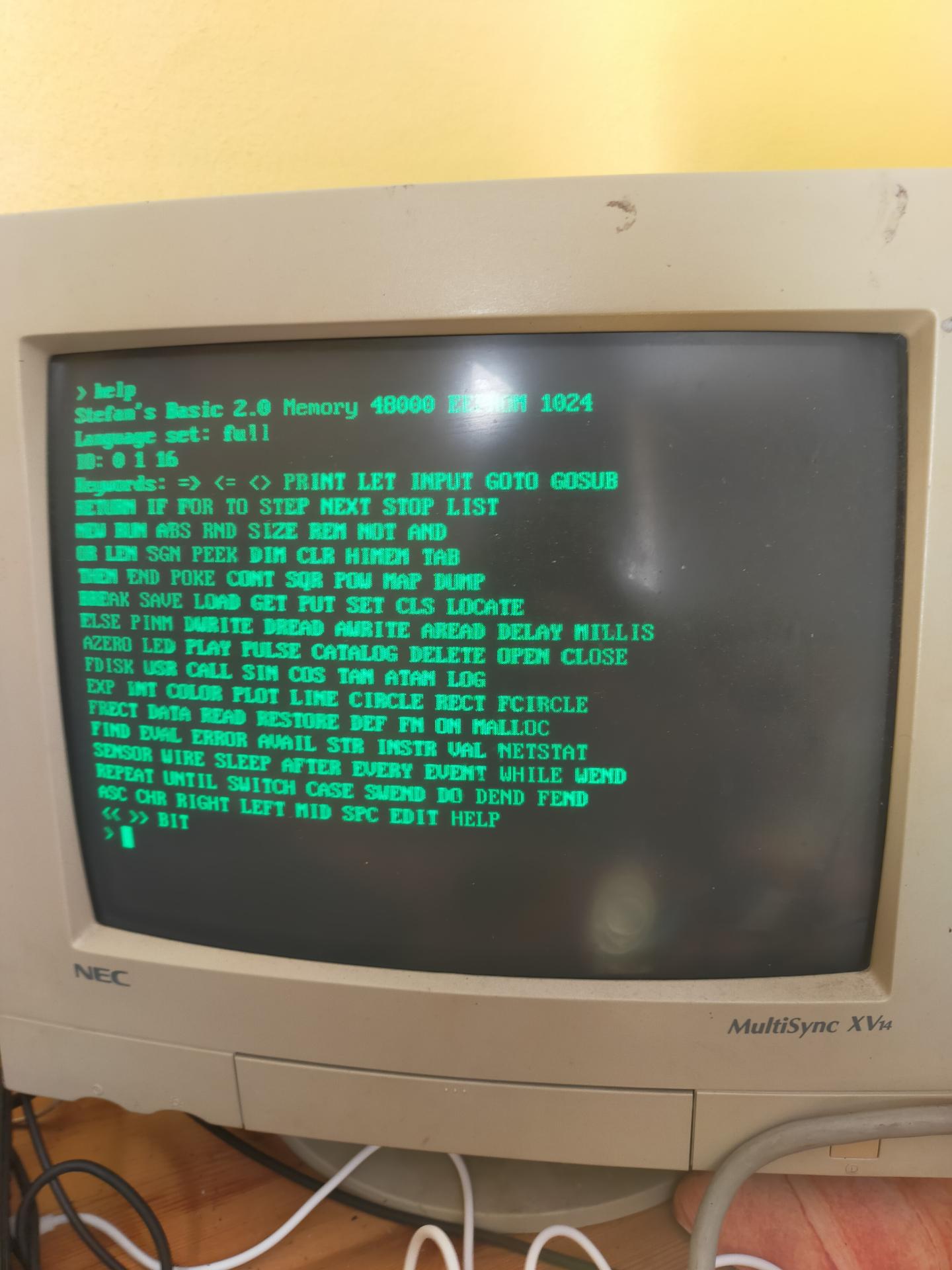 A grubby beige NEC CRT displaying the HELP command in green text from Stefan's Tiny BASIC.