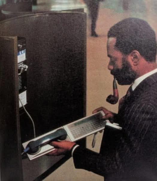 Man with a pipe acoustic couples a modem to a payphone.