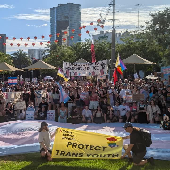 a big crowd of people at a rally. legible on two big banners are the words:

1. TRANS JUSTICE IS HOUSING JUSTICE

2. PROTECT TRANS YOUTH